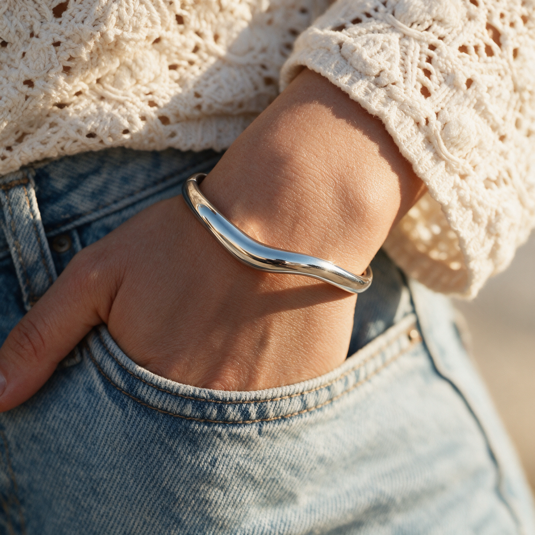 Silver wave bangle worn on wrist, golden hour