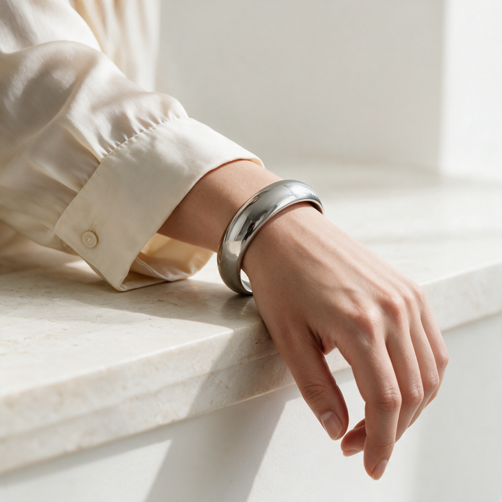 Wide silver bangle worn on wrist, soft studio daylight