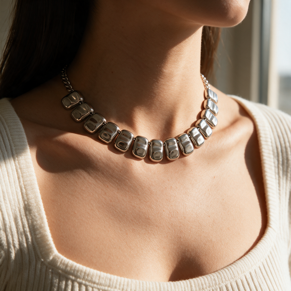 Silver necklace worn on collarbone, warm afternoon light