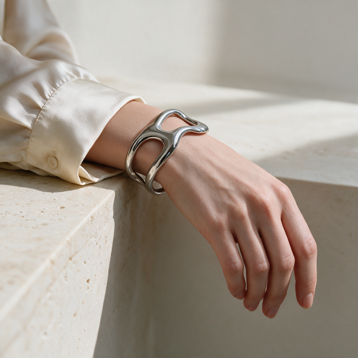 Silver bracelet worn on wrist, soft studio daylight on stone ledge