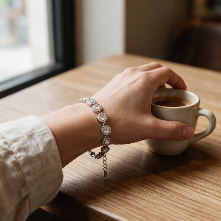 Silver bracelet worn on wrist holding espresso cup, café light