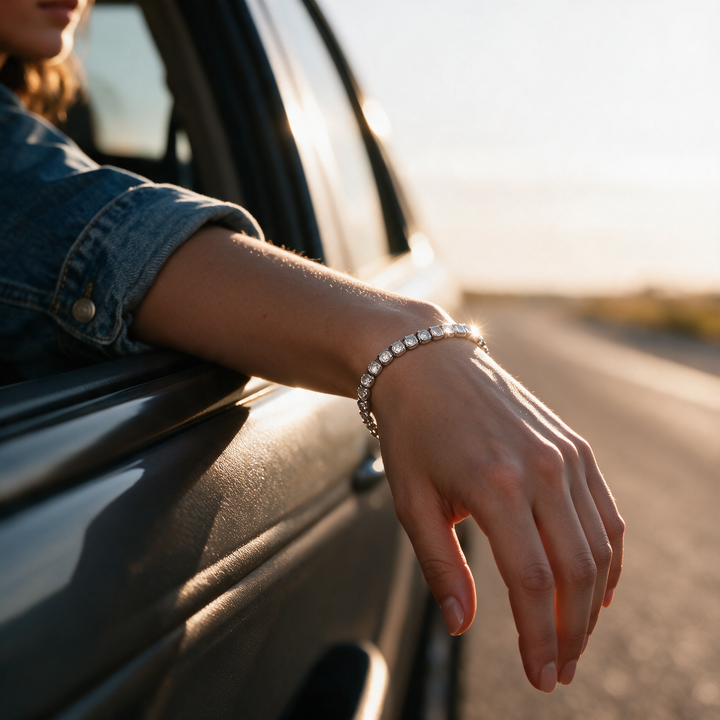 Silver bracelet on forearm resting on car window ledge at sunset