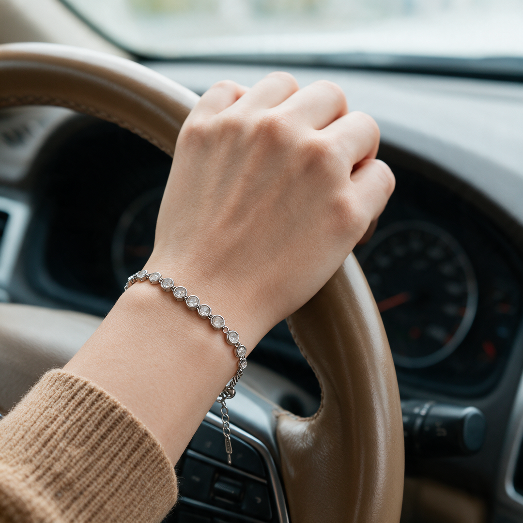 Silver bracelet on hand at leather steering wheel