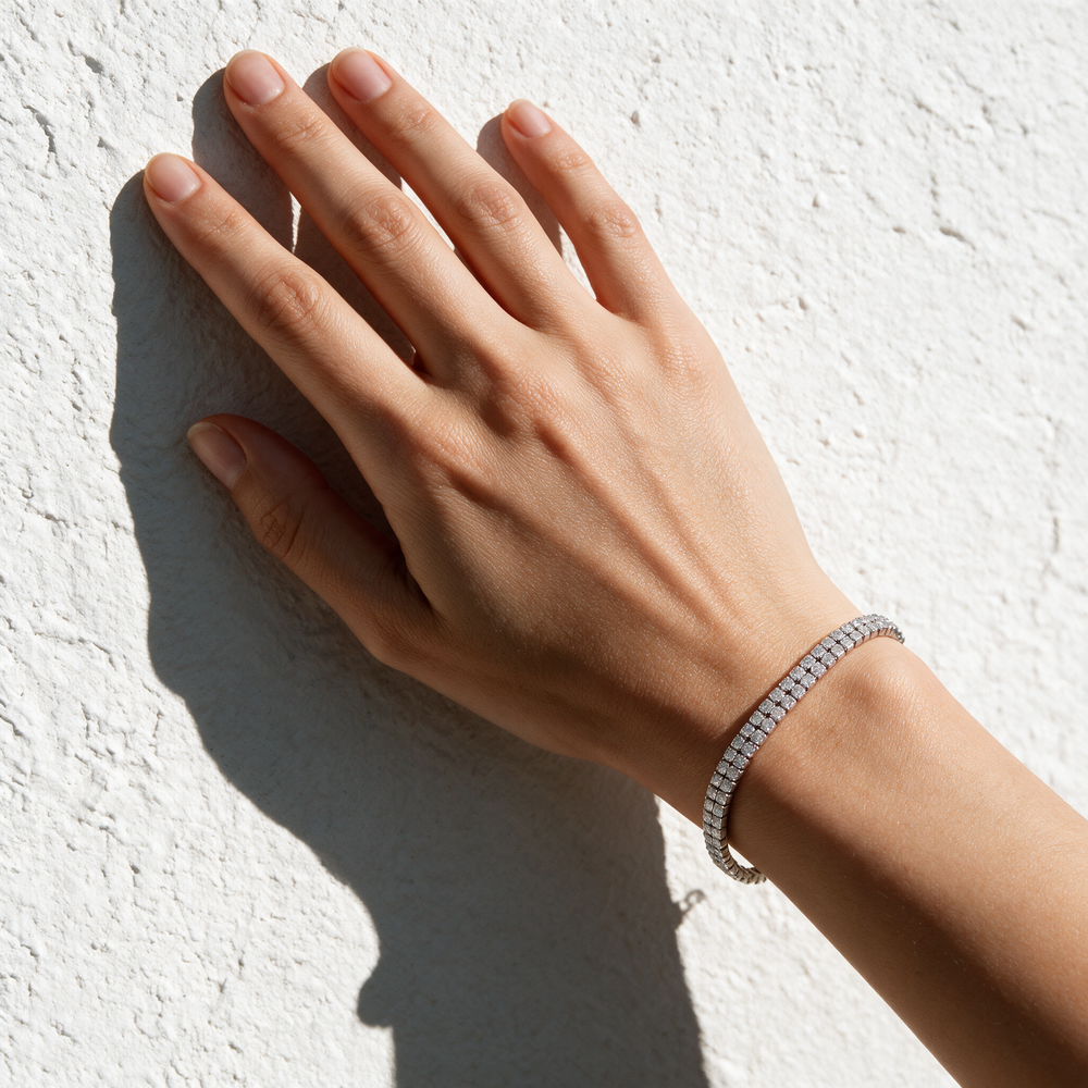 Silver bracelet on hand against white plaster wall, hard sun