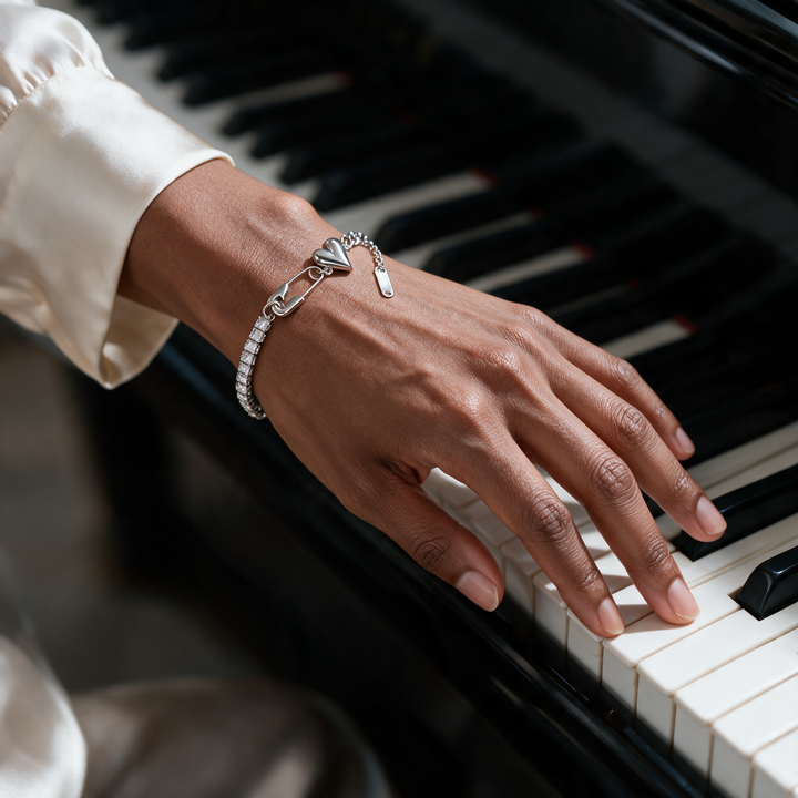 Silver bracelet on hand at piano keys