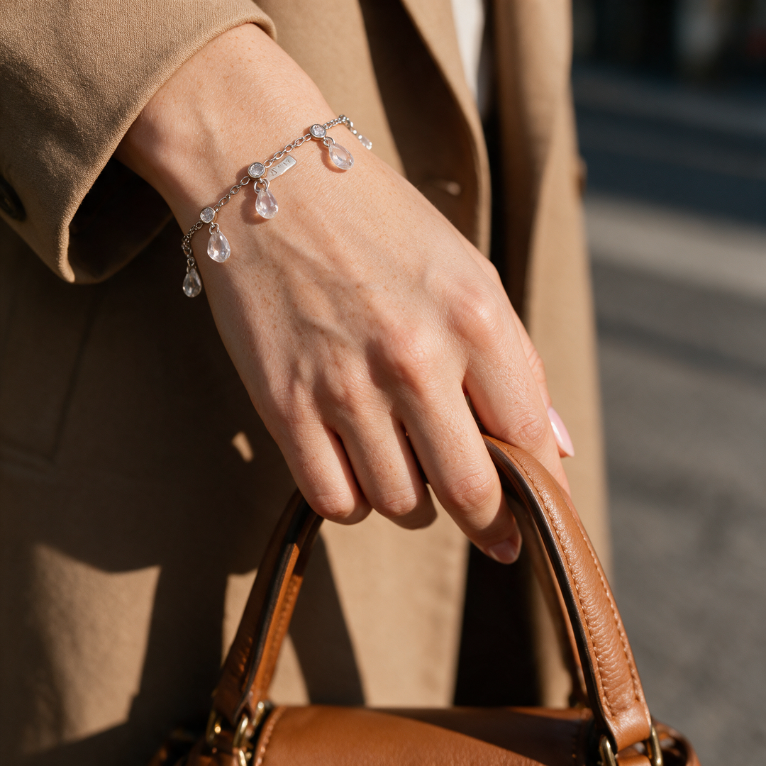 Silver bracelet on hand gripping tan leather bag strap