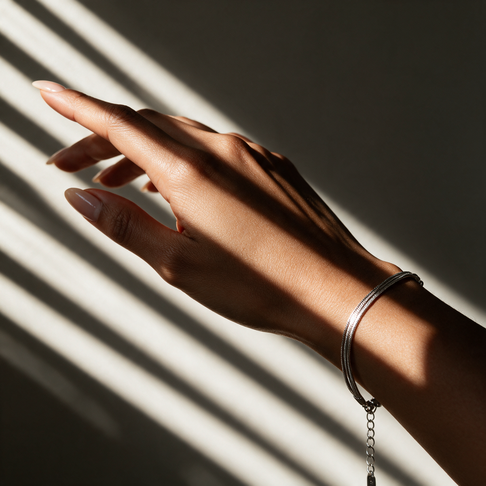 Silver bracelet on hand in striped light from venetian blinds