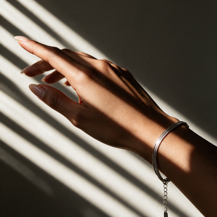 Silver bracelet on hand in striped light from venetian blinds