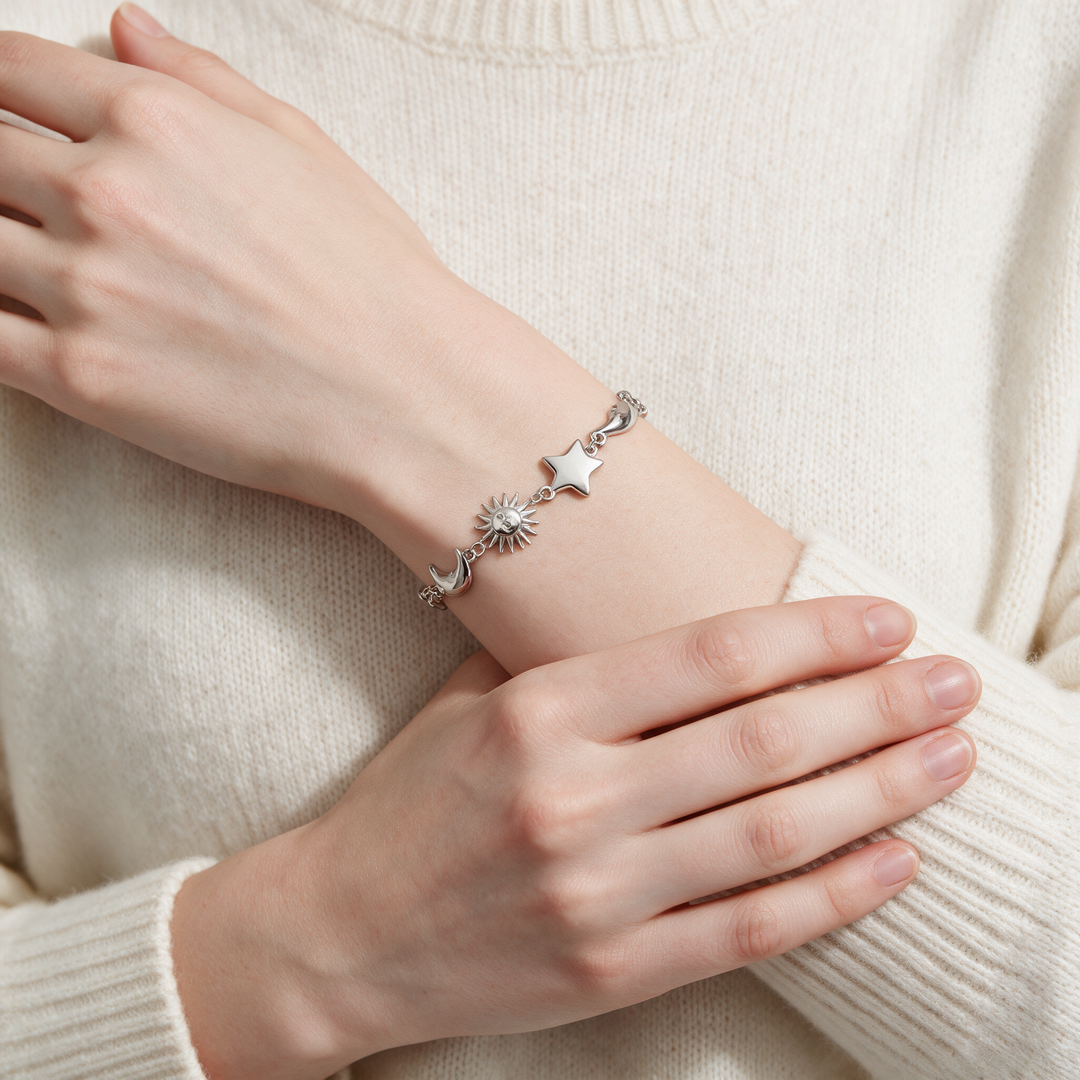 Silver bracelet on crossed forearms over cream cashmere