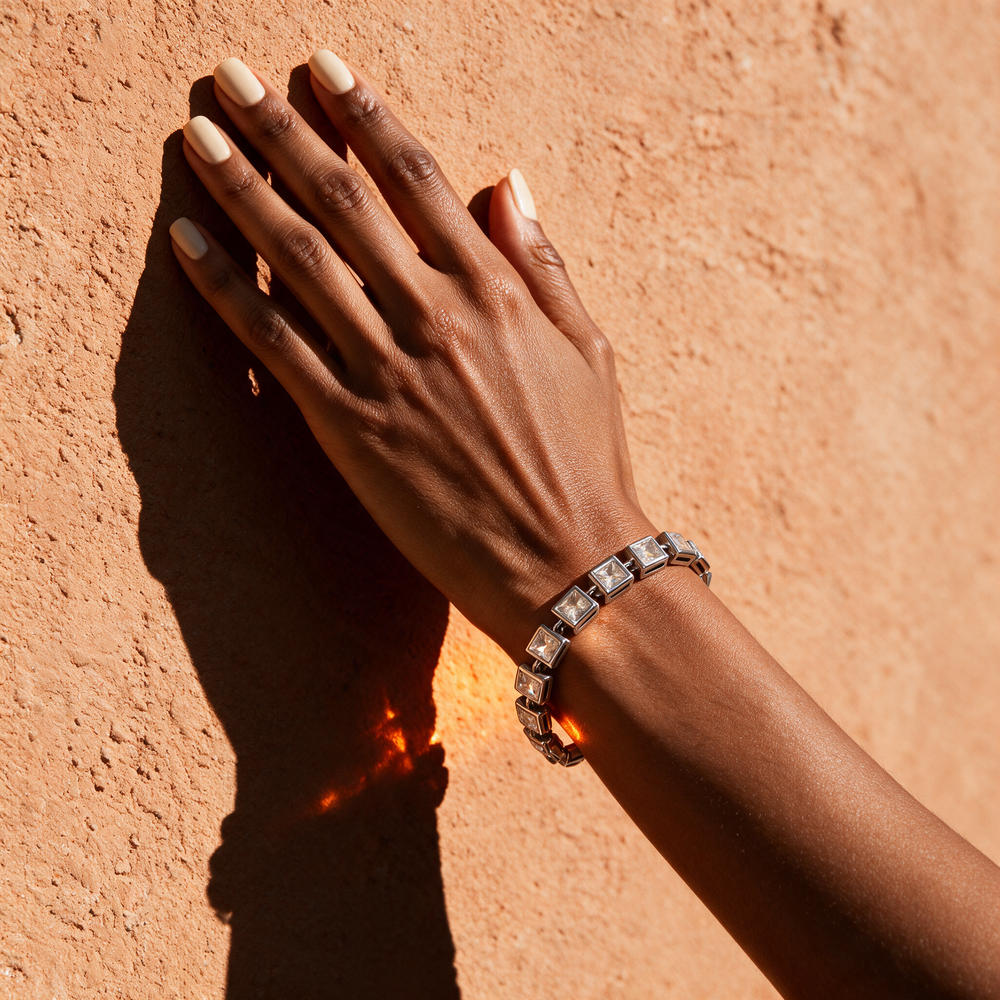 Silver bracelet on hand against terracotta wall, noon sun