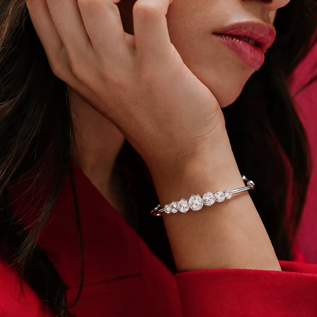 Silver bracelet worn on wrist, hand raised near neck, red top