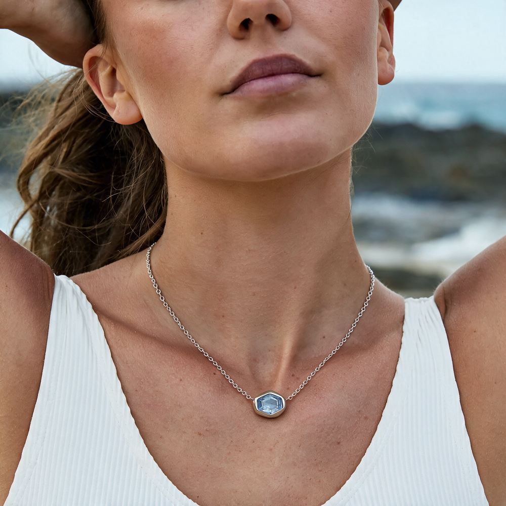 Silver necklace with blue stones worn on neck