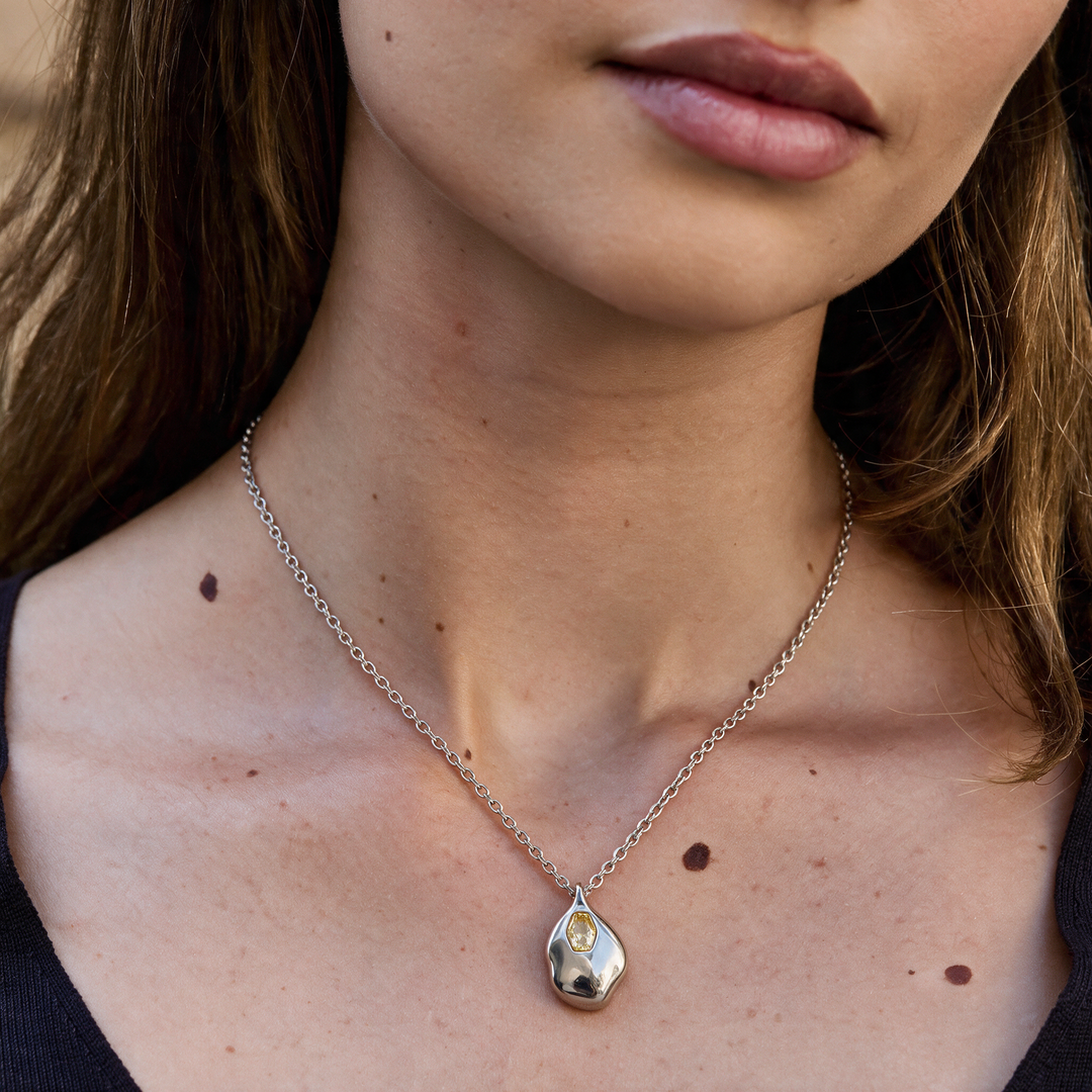 Silver necklace with yellow stones worn on neck