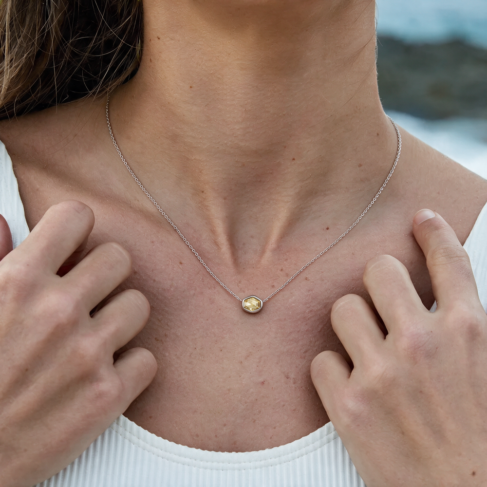 Silver necklace with yellow stone worn on neck