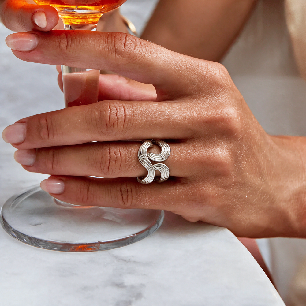 Sculptural ribbed silver wave ring worn on hand