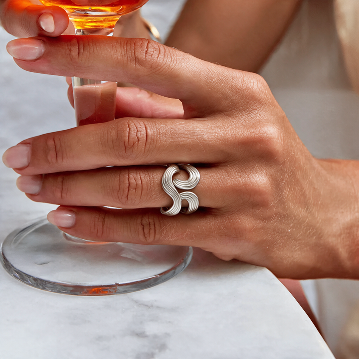 Sculptural ribbed silver wave ring worn on hand